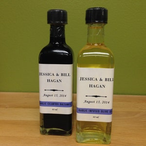 May include: Two glass bottles with labels. The bottles are labeled "Jessica & Bill Hagan" and the date "August 15, 2014". One bottle is labeled "Garlic Cilantro Balsamic" and the other is labeled "Garlic Infused Olive Oil". Both bottles are 60 ml.