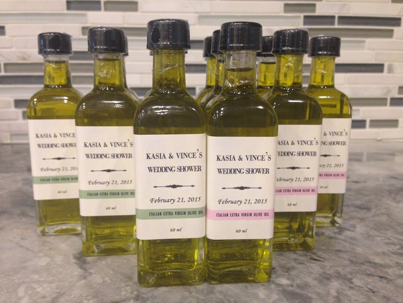 May include: A group of 10 small glass bottles of olive oil with black lids and labels that say "Kasia & Vince's Wedding Shower" and "February 21, 2015".