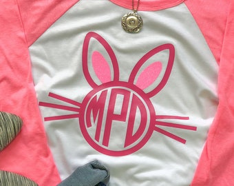 May include: A white and pink baseball tee shirt with a pink bunny rabbit design featuring a monogram in a circle. The monogram is "MPD".