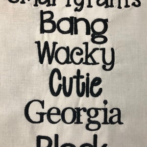 May include: Embroidered text on a white fabric background. The text reads "Smarty Pants Bang Wacky Cutie Georgia Block".