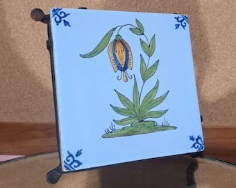 Very beautiful Delft tile that sits in a separate cast iron trivet, both are well marked and both are uniquely beautiful.