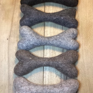 Könnte beinhalten: Fünf Filz-Hundebeine in verschiedenen Grautönen, von Dunkelgrau bis Hellgrau, vertikal in einem Stapel angeordnet.