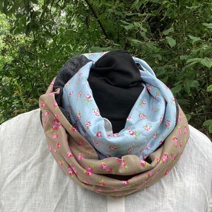 Könnte beinhalten: Ein brauner, blauer und grauer Infinity-Schal mit Blumenmuster. Der Schal ist aus weichem Stoff und perfekt, um sich im Winter warm zu halten.