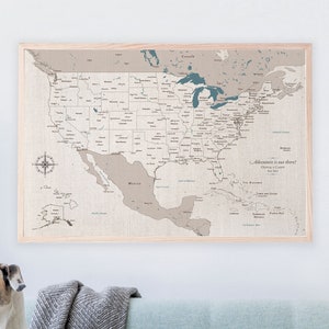 A United States travel map on 100 percent cotton canvas. It is framed and hang above a blue sofa with a dog sitting on it. The USA map is a cotton anniversary gift that is personalized with the names and wedding date of the couple.