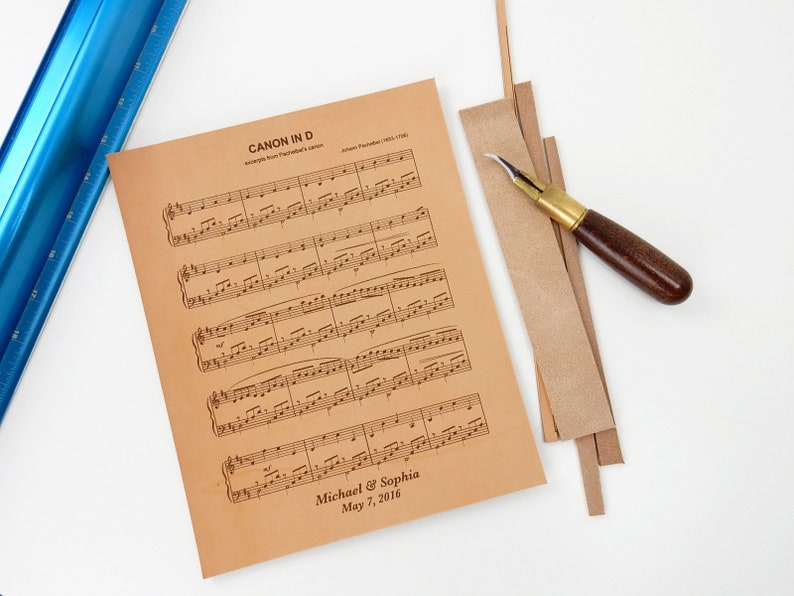 Photograph depicting the meticulous hand-cutting process of leather sheet music to fit the frame size. Prior to cutting, the wedding song was engraved on the leather with personalized details.