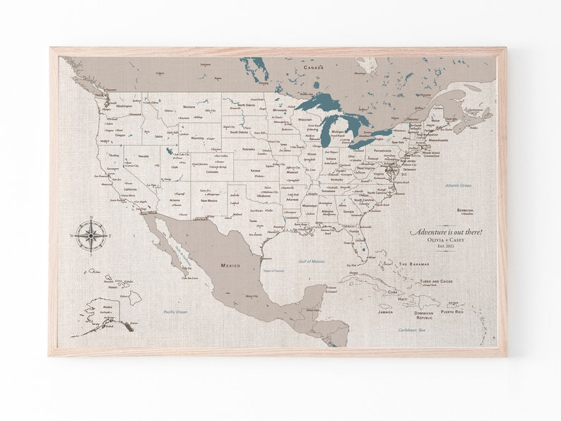 A framed, detailed USA map on 100 percent cotton canvas. The map is detailed with cities, states and capitols marked and labeled. It is on a natural cotton finish in shades of tan and beige with blue lakes and water detail. Personalized with names.