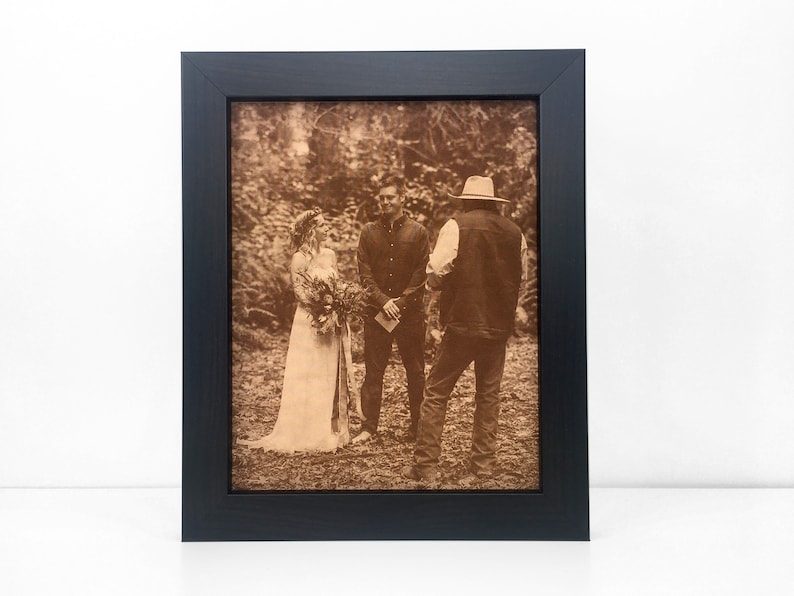 A wedding ceremony photo laser engraved on leather and framed in a dark walnut frame. The photo is an outdoor wedding, very casual and country setting. The leather photo has a warm sepia tone.