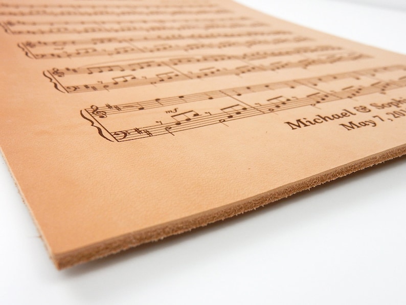 Detailed close-up of the engraved sheet music leather anniversary gift, capturing the real leathers thickness and the intricate engraving from a unique angle.