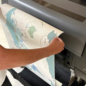 Mike Wilkeson carefully removes a personalized push pin travel map from our professional large format printer in our Luray, Virginia studio. Each map is designed, printed, finished, and prepared by husband-and-wife team (Mike and Jess) from start to finish. Creating a thoughtfully made travel map and keepsake to ship to you worldwide.