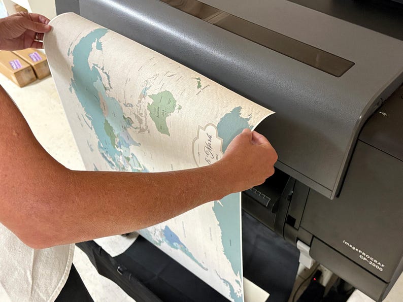 Mike Wilkeson carefully removes a personalized push pin travel map from our professional large format printer in our Luray, Virginia studio. Each map is designed, printed, finished, and prepared by husband-and-wife team (Mike and Jess) from start to finish. Creating a thoughtfully made travel map and keepsake to ship to you worldwide.