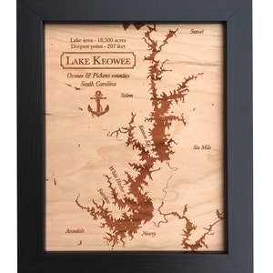 May include: A wooden map of Lake Keowee in South Carolina, showing the lake's outline and various points of interest, including Salem, Sunset, White Harbor, and Six Mile. The map is framed in black and has the text "Lake area - 18,500 acres, Deepest point - 297 feet, LAKE KEOWEE, Oconee & Pickens counties, South Carolina" at the top.