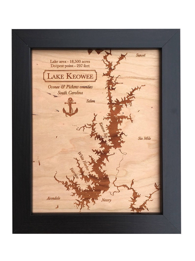 May include: A wooden map of Lake Keowee in South Carolina, showing the lake's outline and various points of interest, including Salem, Sunset, White Harbor, and Six Mile. The map is framed in black and has the text "Lake area - 18,500 acres, Deepest point - 297 feet, LAKE KEOWEE, Oconee & Pickens counties, South Carolina" at the top.