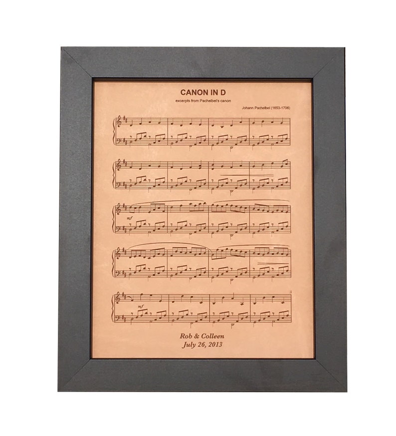 Personalized leather-engraved sheet music elegantly framed in dark walnut. Featuring a beloved wedding ceremony song with the couple's first names and wedding date.