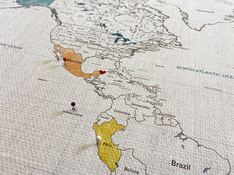 Sample image shows countries watercolor painted in with pins and a special heart on a specific location. Each map is printed on 100 percent cotton canvas. Water resistant to allow watercolor paints.
