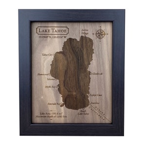 May include: A wooden map of Lake Tahoe, framed in black, with the lake's outline carved out. The map includes the names of towns and points of interest around the lake, including Tahoe City, Homewood, Glenbrook, Emerald Bay, and Zephyr Cove. The map also includes the coordinates of Lake Tahoe: 39.0968&deg; N, 120.0324&deg; W. The map also includes the lake's area (191.6 mi&sup2;) and maximum depth (1,645 feet).
