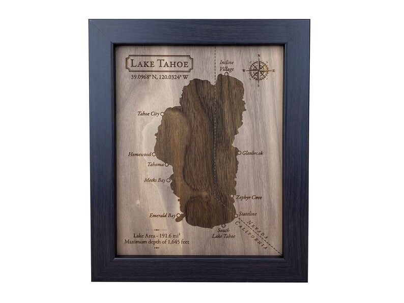May include: A wooden map of Lake Tahoe, framed in black, with the lake's outline carved out. The map includes the names of towns and points of interest around the lake, including Tahoe City, Homewood, Glenbrook, Emerald Bay, and Zephyr Cove. The map also includes the coordinates of Lake Tahoe: 39.0968&deg; N, 120.0324&deg; W. The map also includes the lake's area (191.6 mi&sup2;) and maximum depth (1,645 feet).
