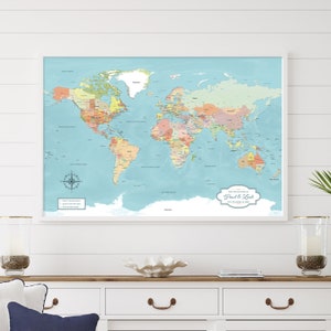 blue push pin world map, personalized with names and date and custom map legend. This detailed world map includes major cities labeled and 100 map pins to track your travels. Framed in a white frame and hanging on ship lap coastal wall decor.