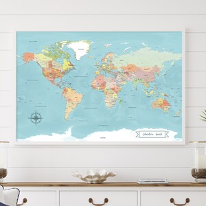 colorful blue world travel map, with multi colored countries and vivid blue ocean. The map includes glacier detail for Antarctica. It features a custom banner, that can be personalized, this one says Adventure Awaits. It is framed & hanging on wall