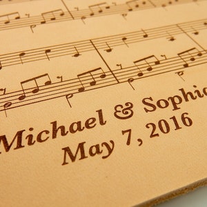 Customized leather anniversary sheet music featuring engraved names and date beneath the sheet music engraving. Crafted on genuine leather.