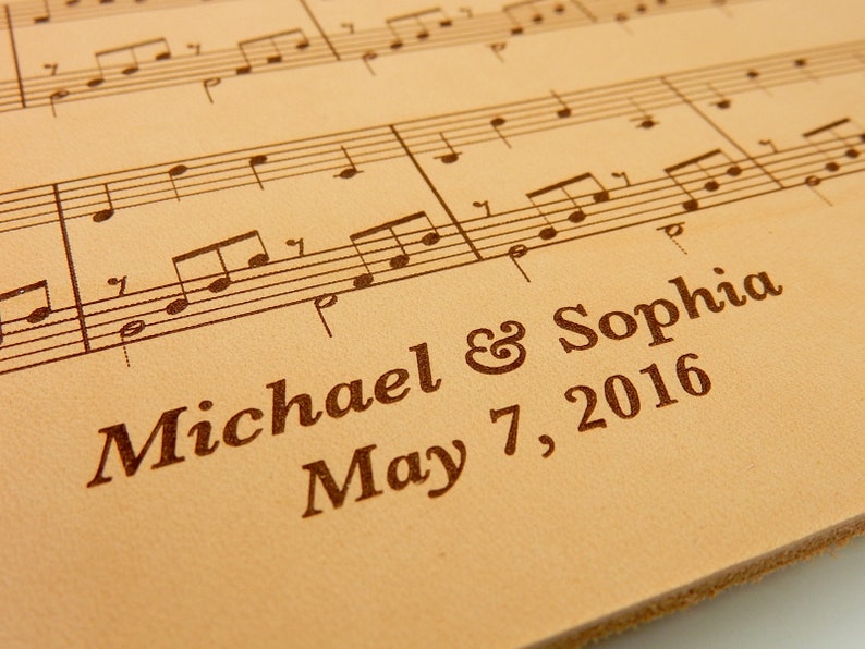 Customized leather anniversary sheet music featuring engraved names and date beneath the sheet music engraving. Crafted on genuine leather.