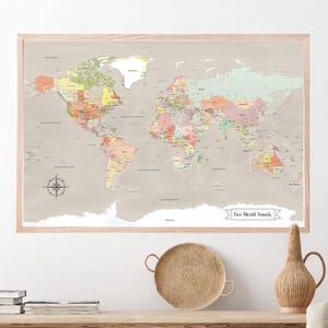 May include: A framed world map with a beige background and colorful country borders. The map is titled "Our World Travels" and features a compass in the bottom left corner.