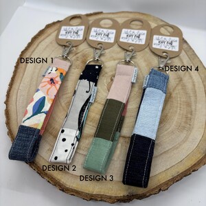 May include: Four different key fob designs with a patchwork fabric pattern. The designs include floral, black and white polka dot, green and brown, and blue and white.