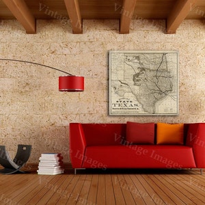 Pode incluir: Um mapa vintage do estado do Texas, impresso em preto e branco, est&aacute; emoldurado e pendurado em uma parede de uma sala de estar. O mapa &eacute; cercado por um sof&aacute; vermelho, um abajur de ch&atilde;o com uma c&uacute;pula vermelha e um piso de madeira.