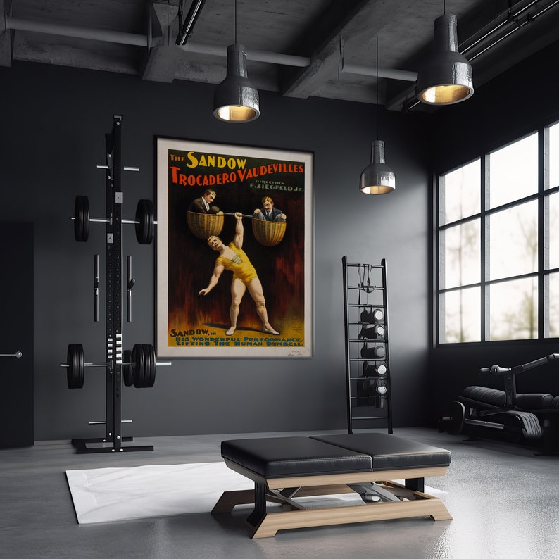 Puede incluir: Un cartel vintage que anuncia "The Sandow Trocadero Vaudevilles" con un hombre fuerte levantando dos hombres en cestas. El cartel se exhibe en un gimnasio moderno con equipo de levantamiento de pesas.