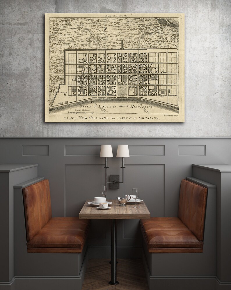 May include: A vintage map of New Orleans, Louisiana, showing the city's layout and streets. The map is printed on a cream-colored paper and framed in a black frame. The map is hanging on a gray wall.
