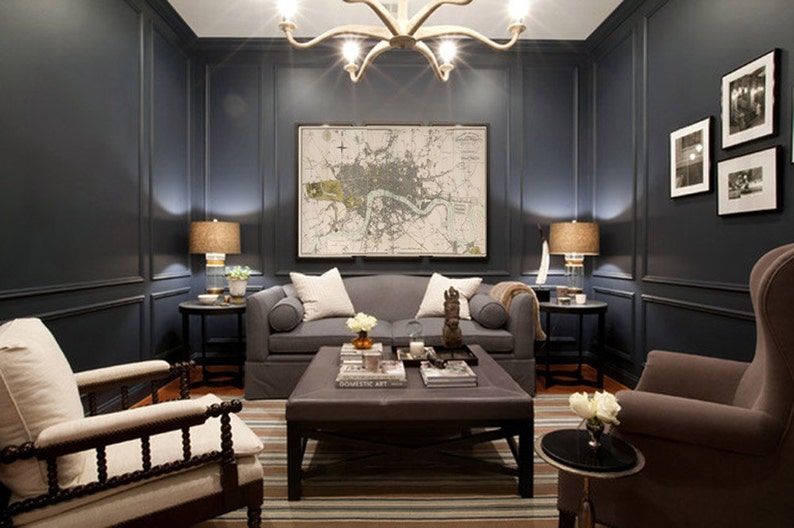 May include: A dark blue living room with a gray sofa, two armchairs, a coffee table, and a map of London on the wall. The room is decorated with lamps, plants, and throw pillows.