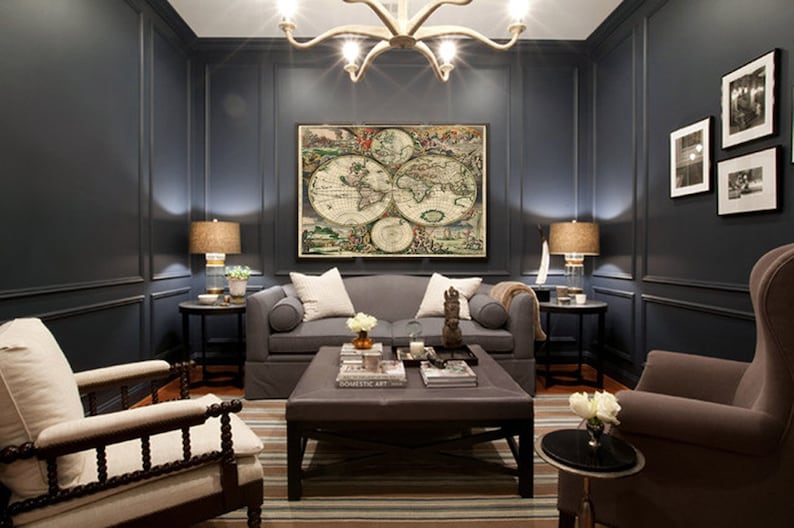 Puede incluir: Una sala de estar azul oscuro con un sof&aacute; gris, dos sillones y una mesa de caf&eacute;. La habitaci&oacute;n cuenta con una gran impresi&oacute;n de mapa del mundo antiguo en la pared, una l&aacute;mpara de ara&ntilde;a y dos l&aacute;mparas.