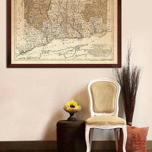 May include: A framed antique map of Connecticut, with the title "Connecticut" in a circle at the bottom right corner. The map is in shades of brown and beige, with a brown frame.