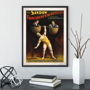 Puede incluir: Un cartel vintage que anuncia una actuaci&oacute;n de Sandow, un hombre fuerte, en los Trocadero Vaudevilles. El cartel muestra a un hombre levantando a dos hombres en cestas, con el texto "The Sandow Vaudevilles Trocadero Direction F. Ziegfeld Jr. Sandow... His Wonderful Performance. Lifting The Human Dumbbell."