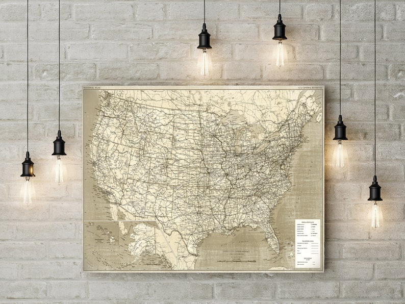 Puede incluir: Un mapa vintage de los Estados Unidos con l&iacute;neas en blanco y negro que muestran carreteras y ferrocarriles. El mapa est&aacute; enmarcado y colgado en una pared de ladrillo con varias l&aacute;mparas de bombilla Edison colgadas encima.