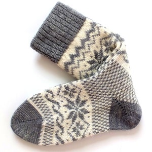 May include: A pair of gray and white knitted socks with a snowflake pattern.