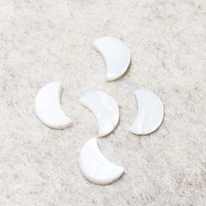May include: Five white crescent moon shaped shell beads.