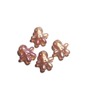 May include: Four gingerbread man-shaped charms in a light brown color. The charms are made of a translucent material and have a slightly shiny finish.