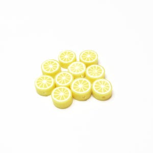 May include: A group of yellow lemon slice shaped beads with white centers.