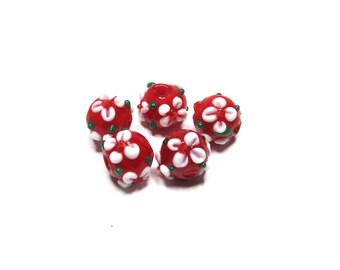 Puede incluir: Cinco cuentas redondas de vidrio rojo con diseños de flores blancas y detalles verdes. Las cuentas tienen un acabado brillante. Ideales para la creación de joyas y proyectos de artesanía.