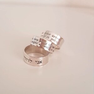May include: Three silver rings with engraved text. The top ring reads "If your arrows never point", the middle ring reads "You stop doing things I might as well be d", and the bottom ring reads "אך לזה" in Hebrew.
