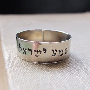 May include: A silver ring with the Hebrew words "Shema Yisrael" engraved on it.