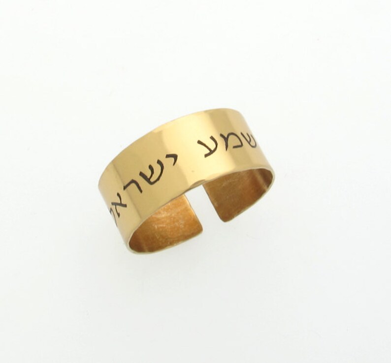 May include: Gold adjustable ring with Hebrew text engraved on the band. The text reads "Shema Yisrael" which translates to "Hear O Israel".