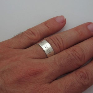 May include: A silver band ring with Hebrew text engraved on the band.