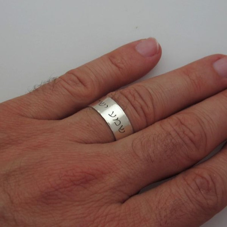 May include: A silver band ring with Hebrew text engraved on the band.