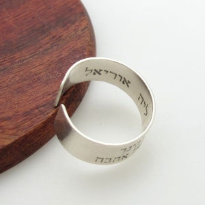 May include: A silver ring with Hebrew text engraved on the band. The text reads "אהבה" and "אלוהים".