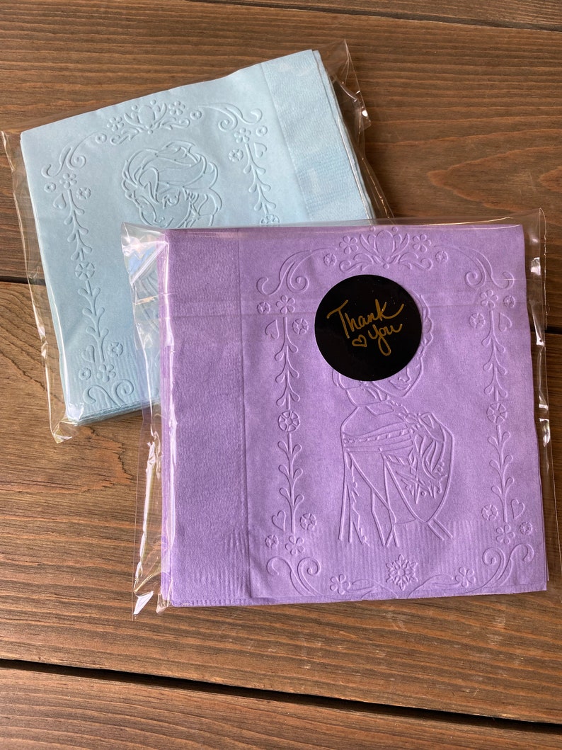 May include: Two packages of blue and purple paper napkins with an embossed design. The purple napkins have a gold sticker that says "Thank You".