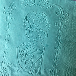 May include: A teal blue kitchen towel with an embossed design of a cartoon character with long blonde hair. The character is wearing a blue dress and has a floral design around the border.