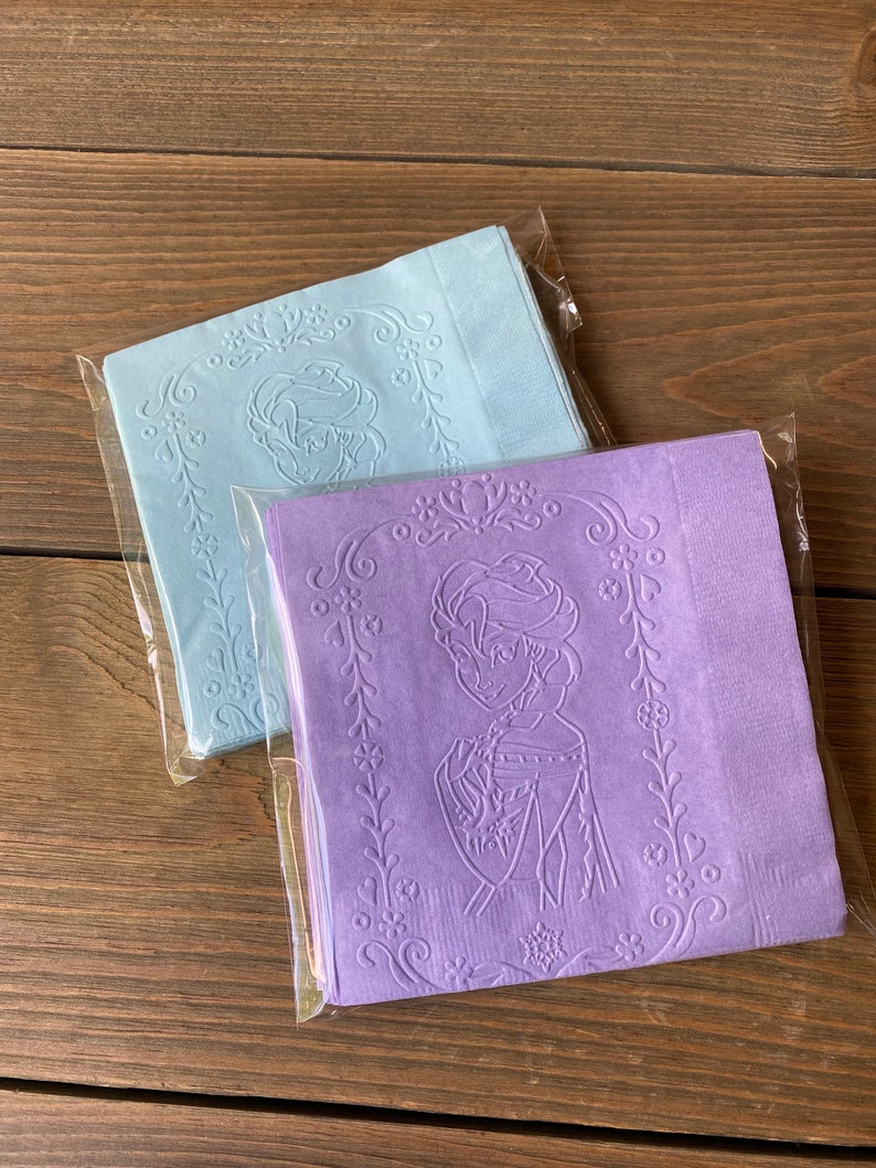 May include: Two packages of paper napkins with an embossed design of a cartoon character. One package is light blue and the other is purple.