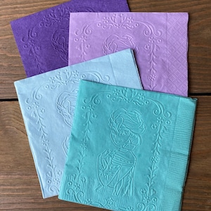 May include: Four paper napkins with an embossed design. The napkins are in shades of purple, blue, and green. The design features a floral border and a character from a popular animated film.