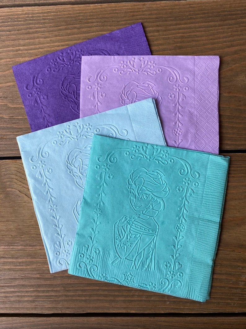 May include: Four paper napkins with an embossed design. The napkins are in shades of purple, blue, and green. The design features a floral border and a character from a popular animated film.
